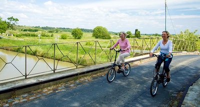 Two women cycling across the bridge on the Canal du Midi